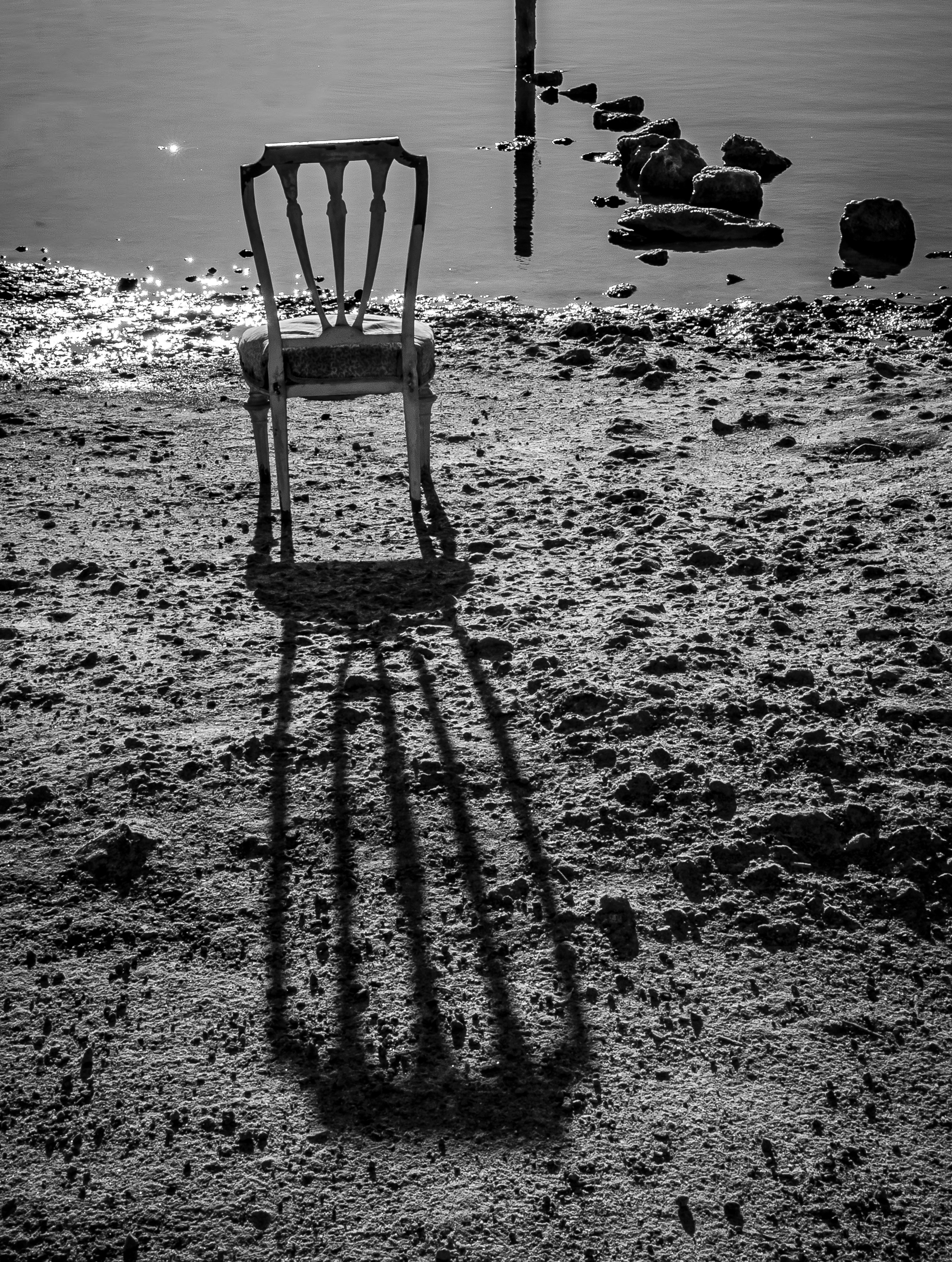 Silla a contraluz con sombra alargada proyectada sobre el barro