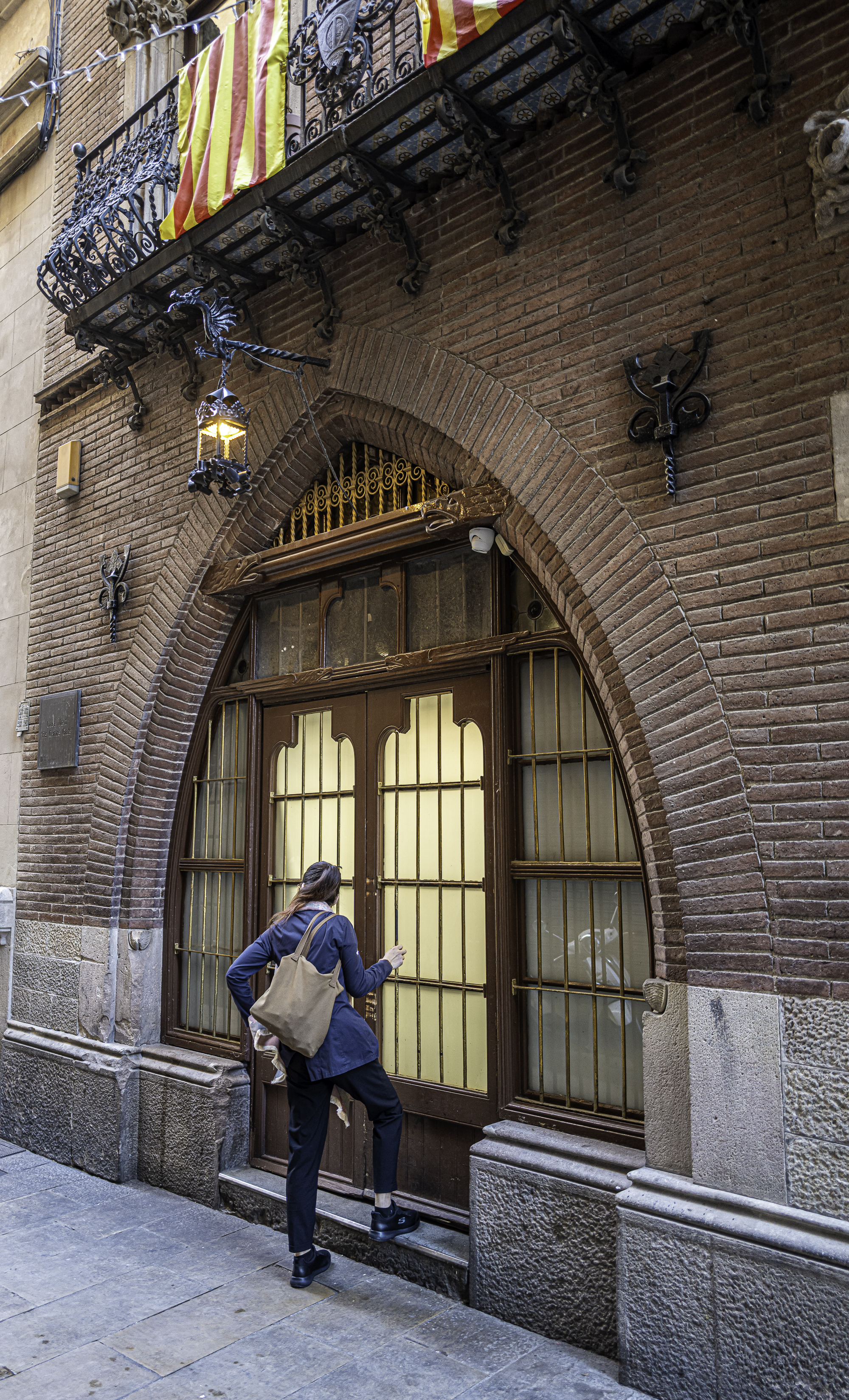 Hombre de espaldas caminando por una calle estrecha del Gótico, luz rasante