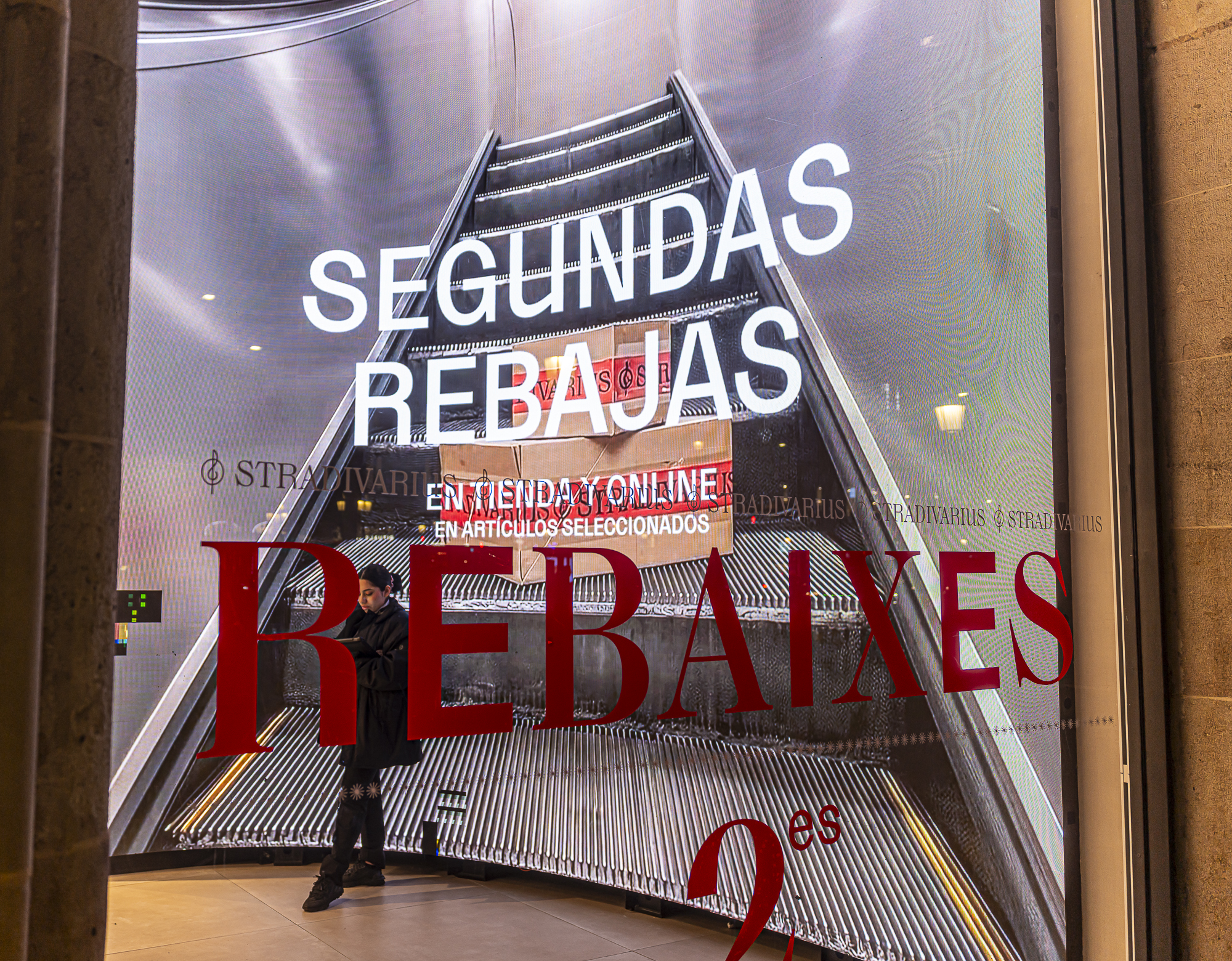 Escaleras mecánicas infinitas con SEGUNDAS REBAJAS y una persona diminuta abajo