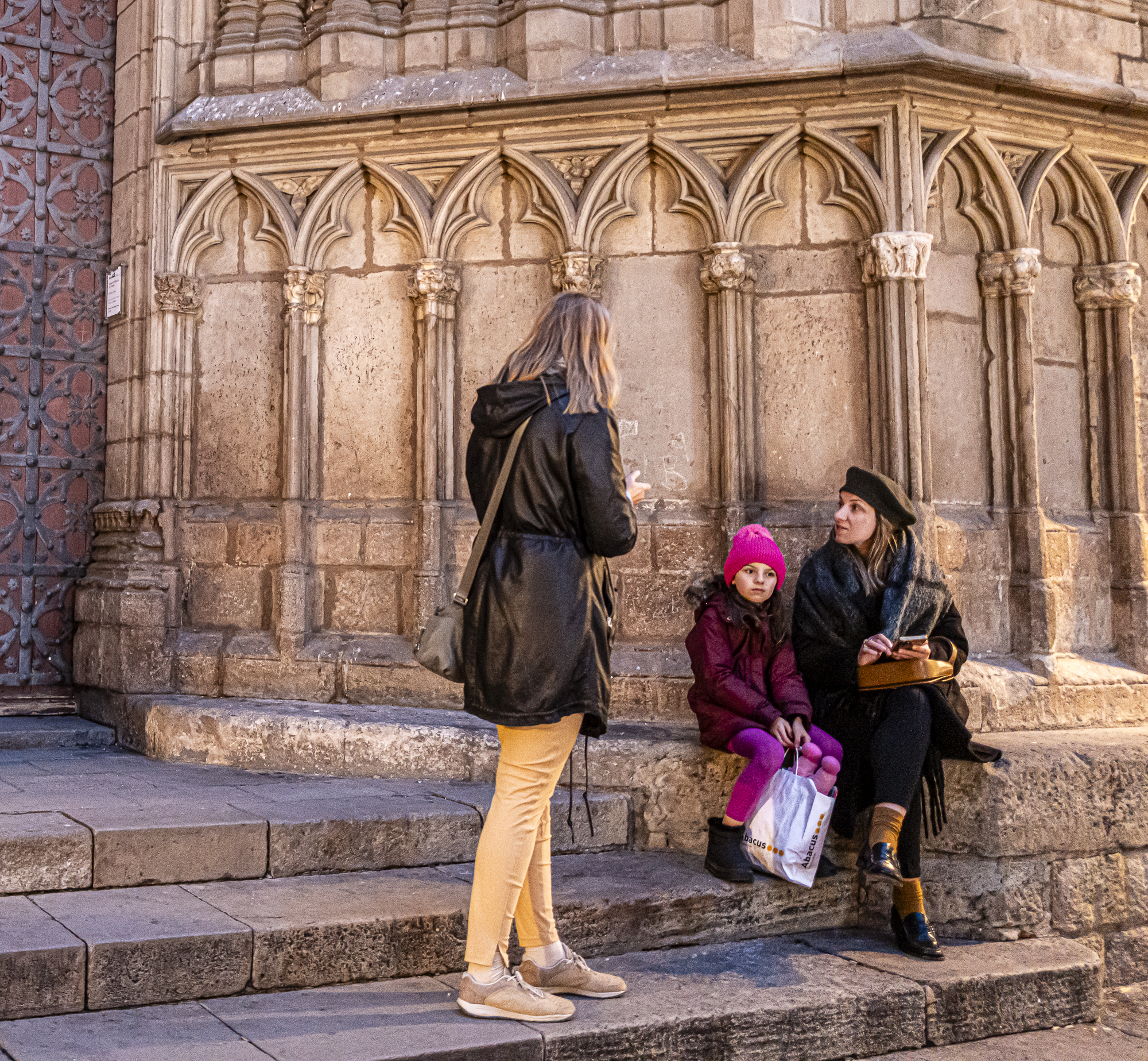 Las tres figuras conversando en los escalones, el santo ya fuera del encuadre
