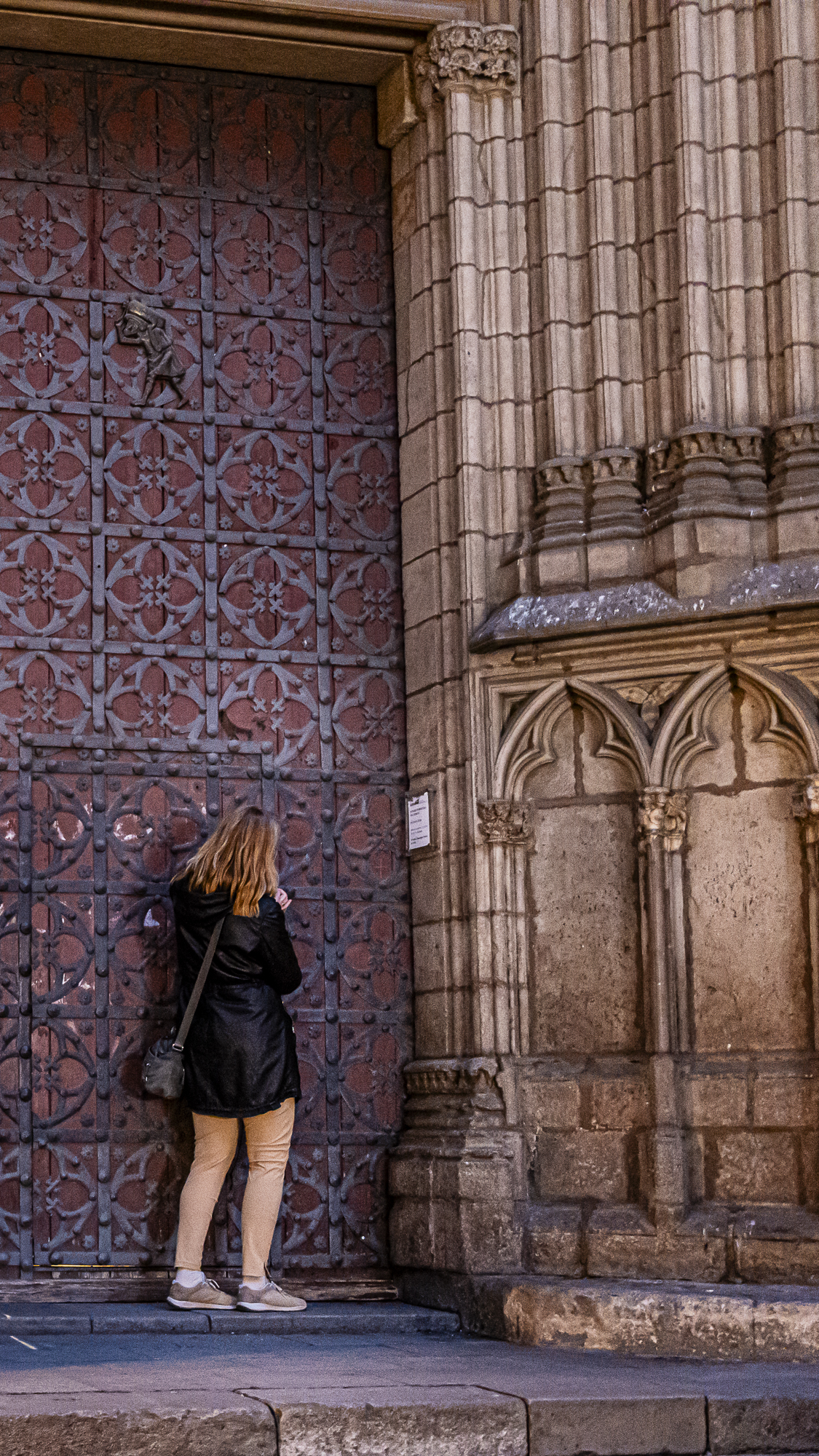 Chica empujando la puerta cerrada de la basílica, vista de cerca