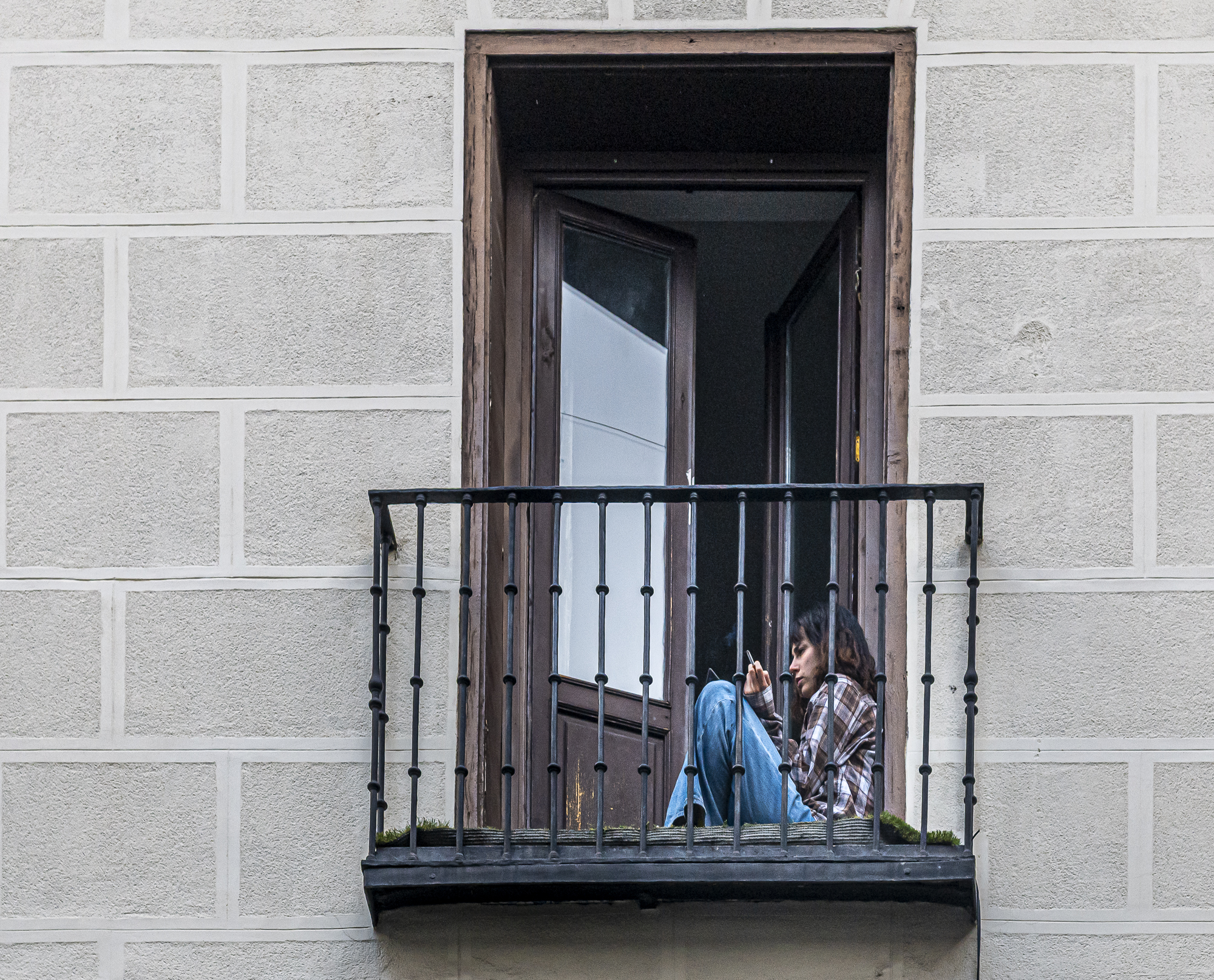 Chica fumando sentada en un balcón tras los barrotes de hierro
