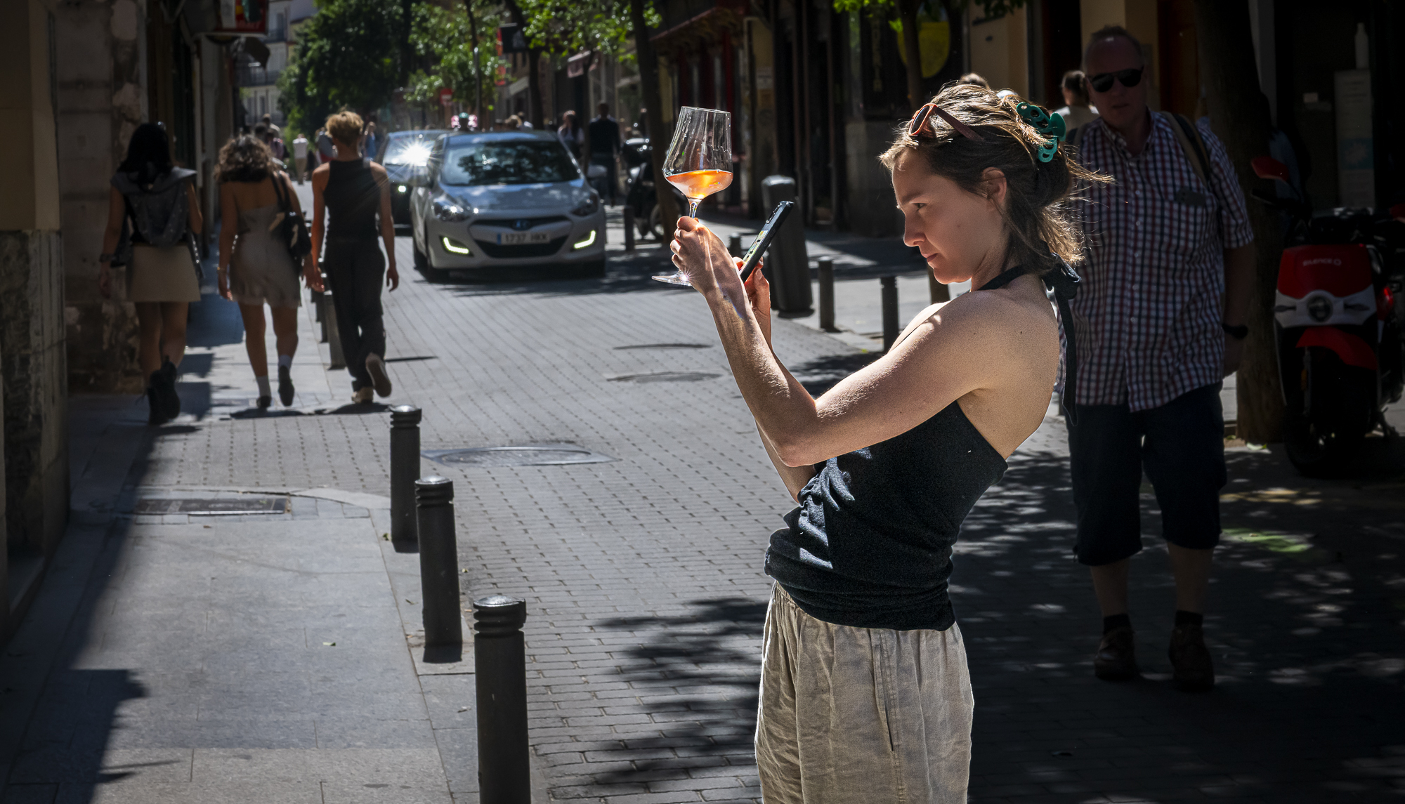 Mujer en la calle con copa de vino y móvil, la distancia como única barrera