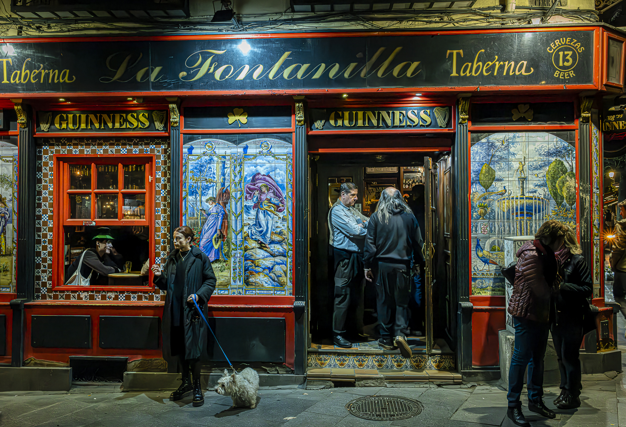 Fachada de la taberna La Fontanilla con azulejos, cristales y múltiples capas de vida