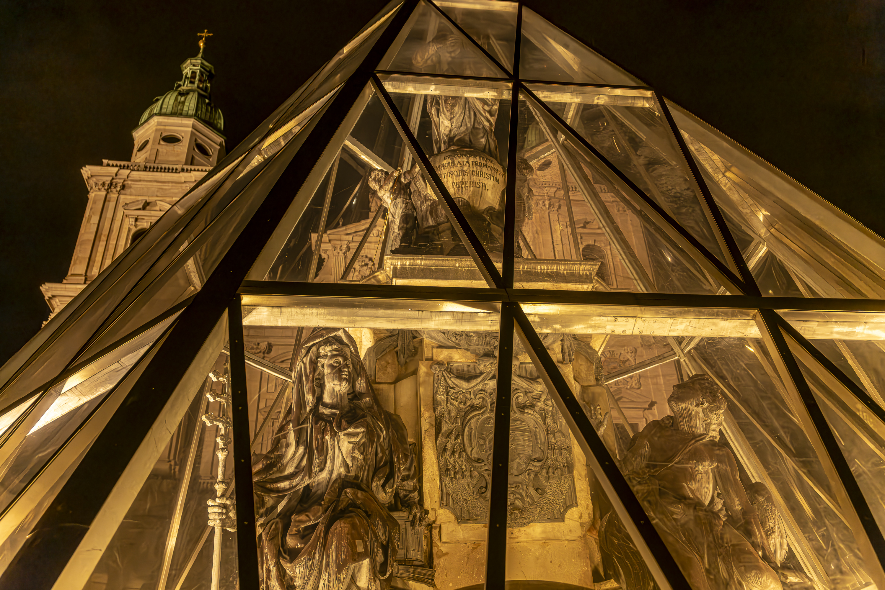 Baroque statues trapped inside glass pyramid, golden night