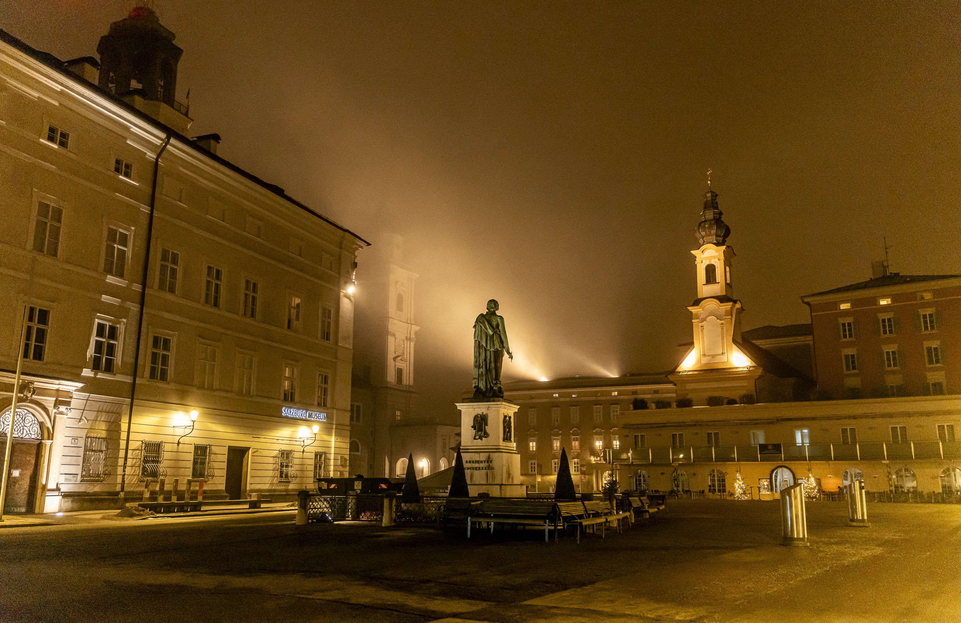 Residenzplatz with Mozart statue wrapped in golden nocturnal fog