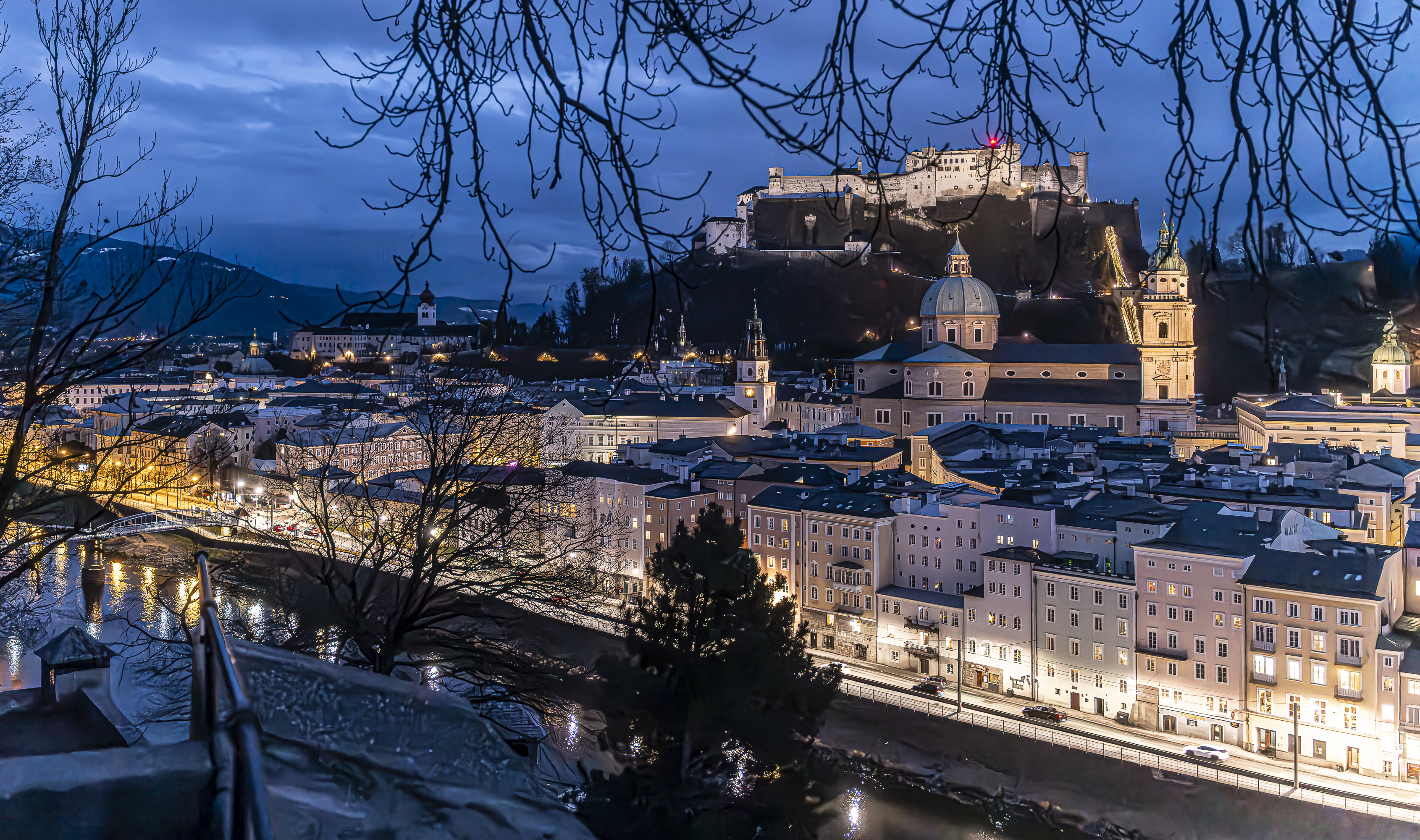 Hohensalzburg fortress through bare branches, staircase, blue hour