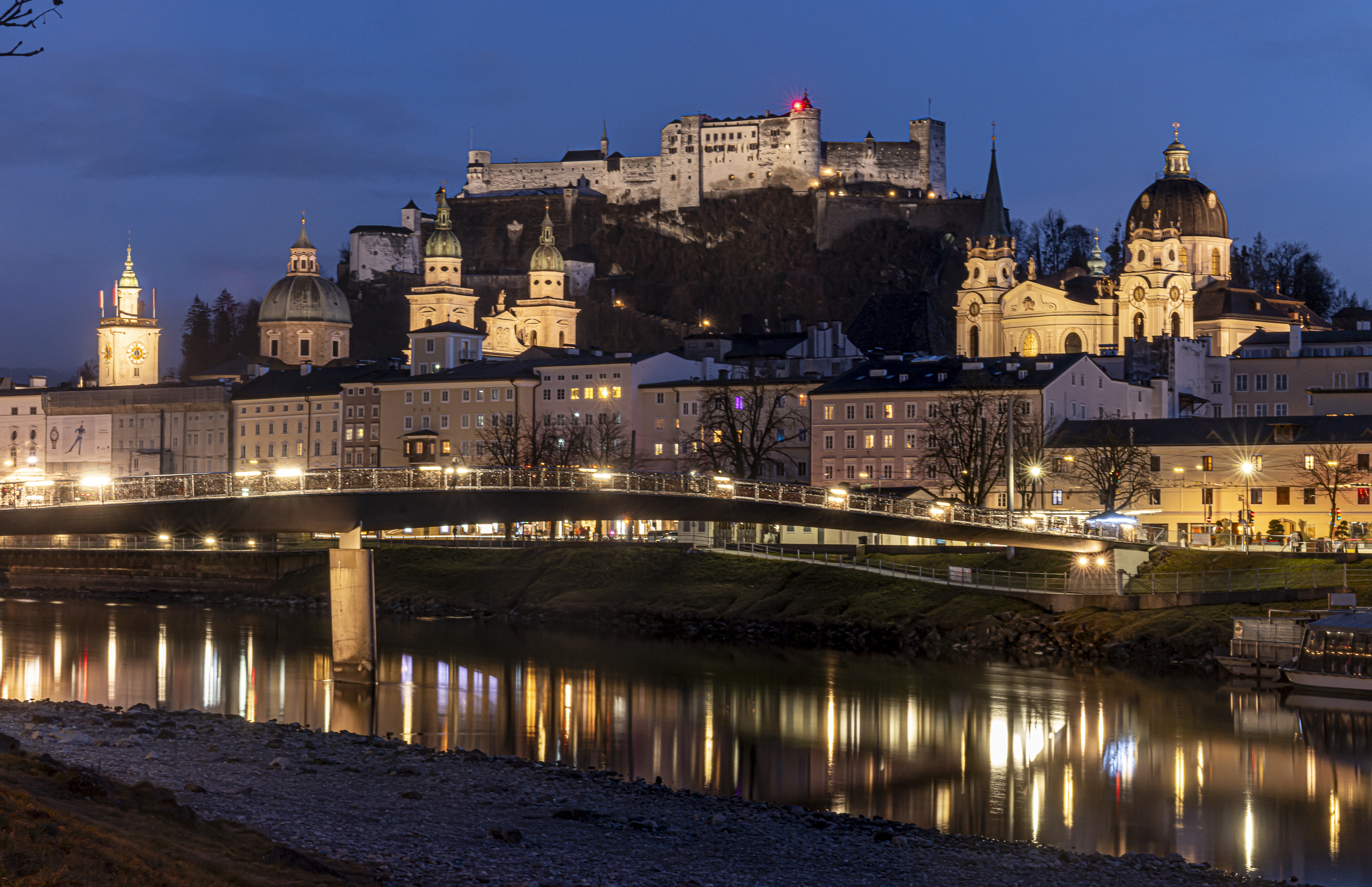Salzburg at night from the Salzach, city lights reflected in the river